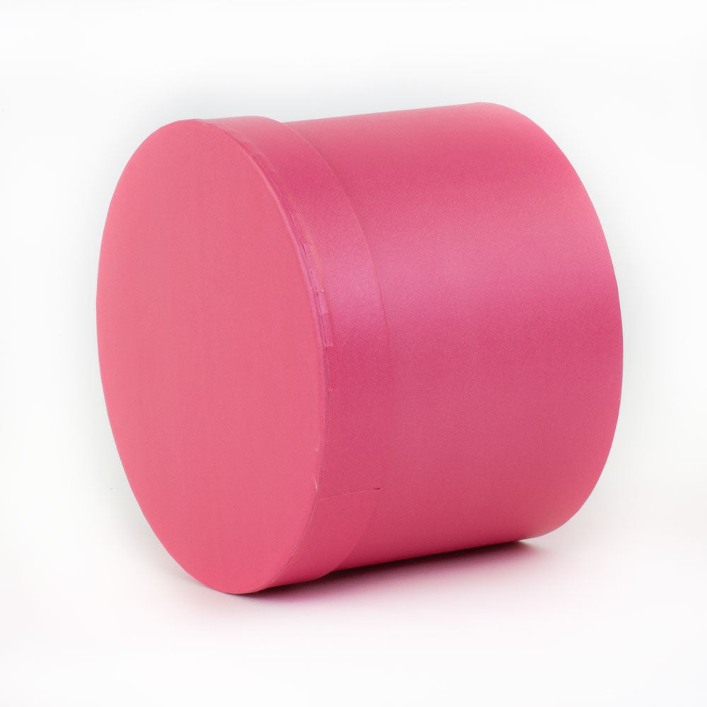 a single strong pink coloured hat box laying on its side at a three quarter aspect