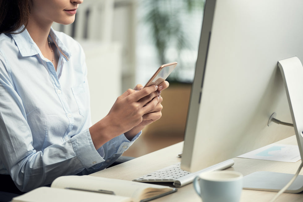 woman sitting office front computer using smartphone