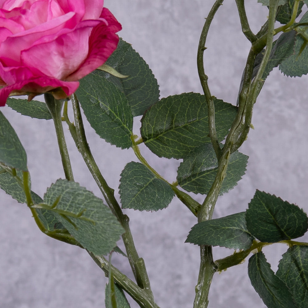 A close up of the leaf detail on a faux dark pink rose spray