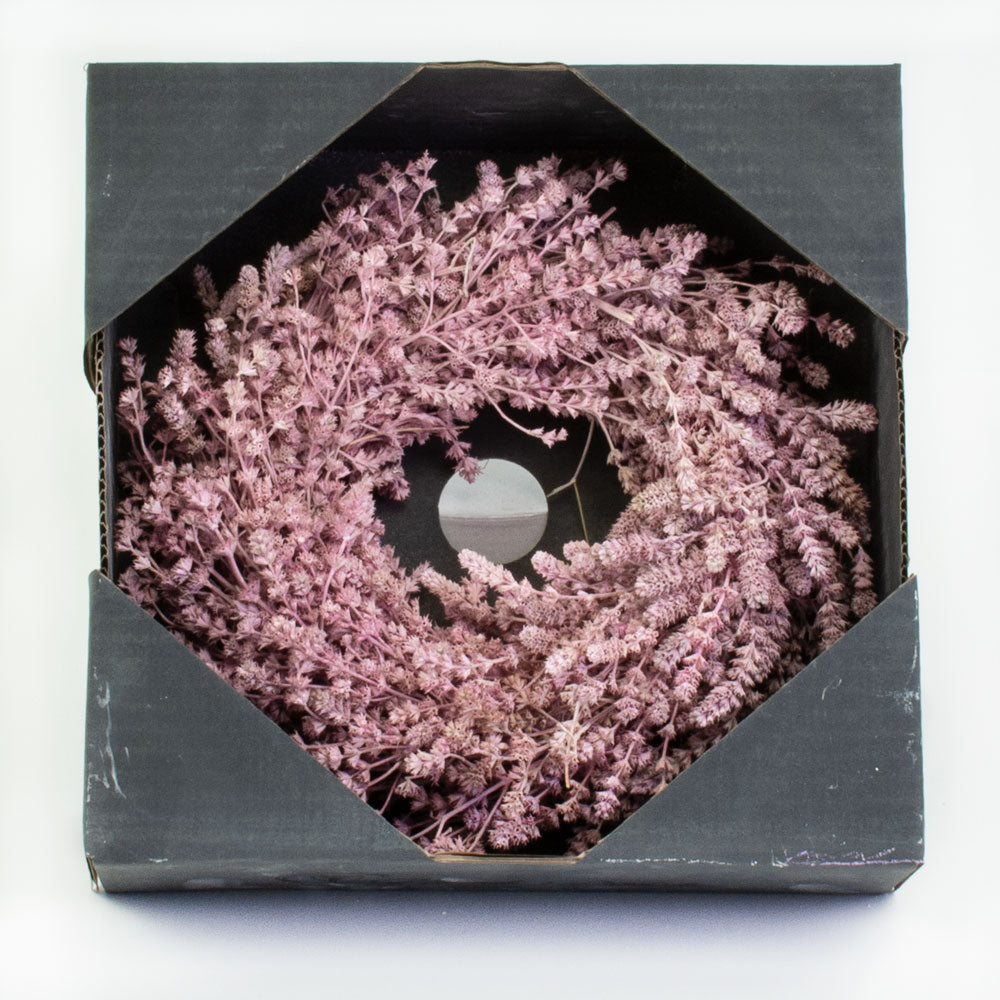 a wreath made of linen herb and painted a chalky pink colour, against a white background