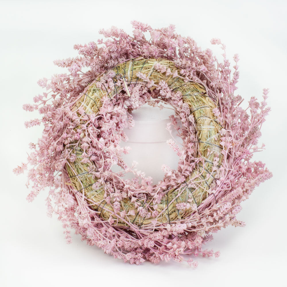 a wreath made of linen herb and painted a chalky pink colour, against a white background