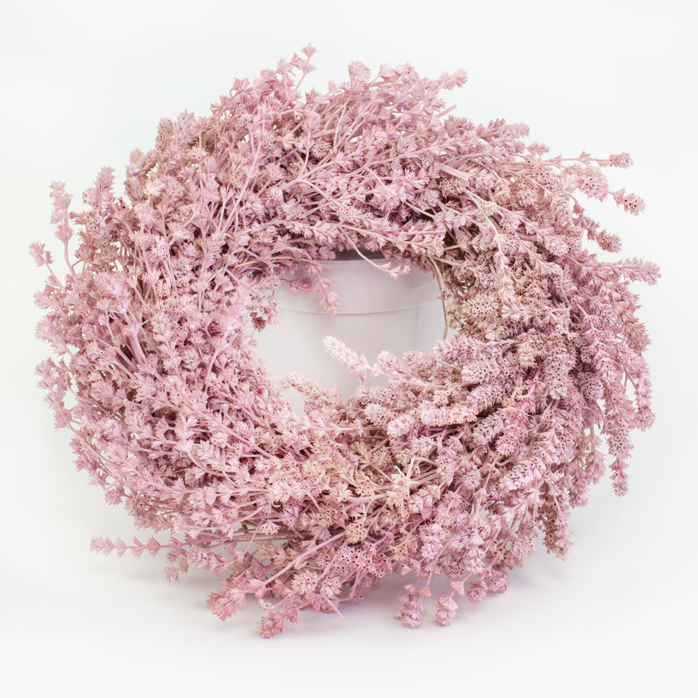 a wreath made of linen herb and painted a chalky pink colour, against a white background