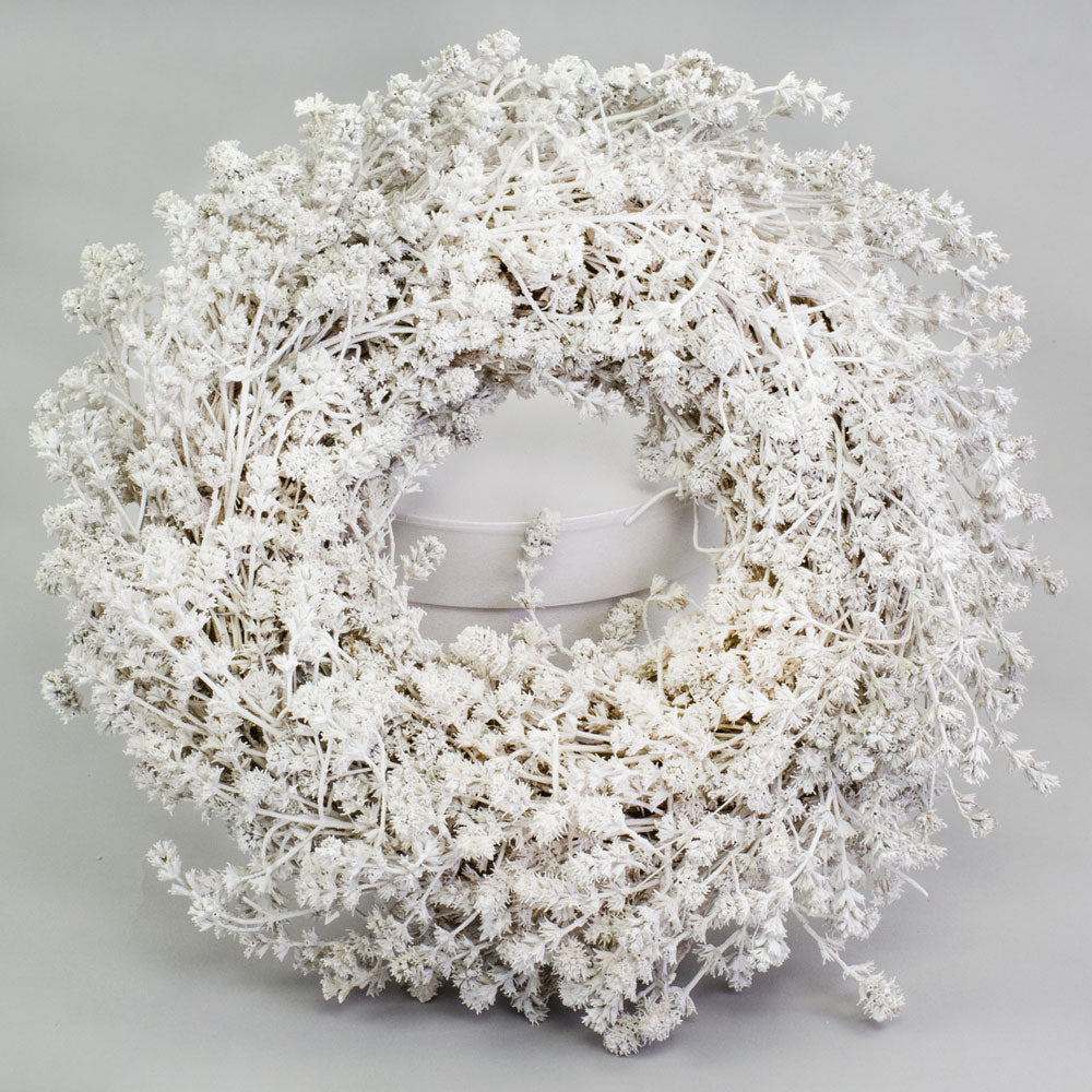 a wreath made of linen herb and painted a chalky white colour, against a white background