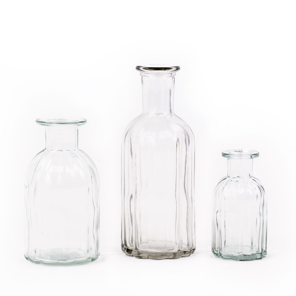 a group of clear glass bottle vases in three different sizes