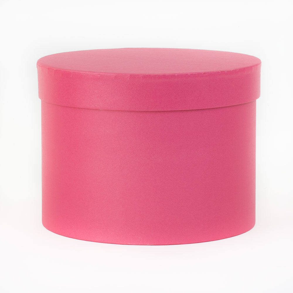 a single strong pink coloured hat box laying on its side at a three quarter aspect