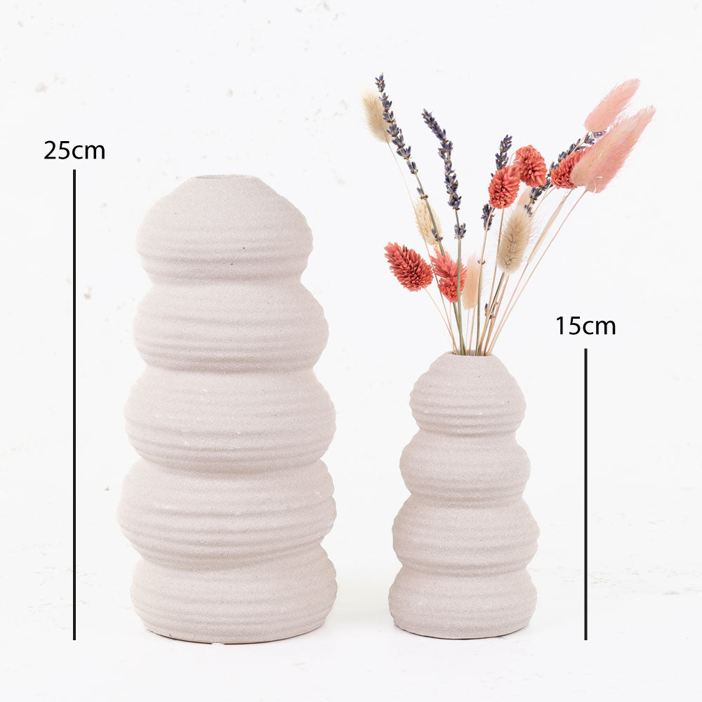 Cream balancing stone vases with flowers.