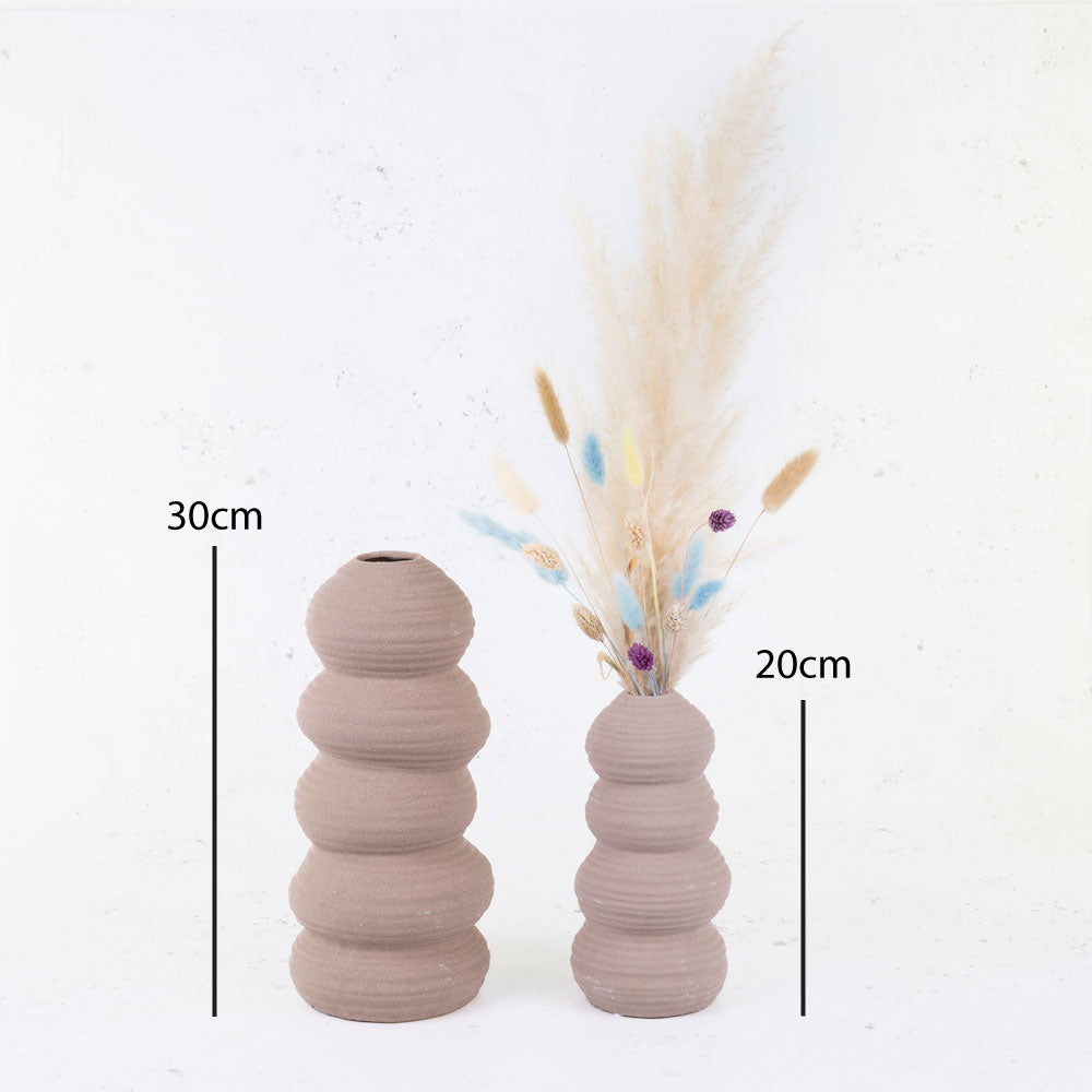 Terracotta balancing stone vases with dried flowers.