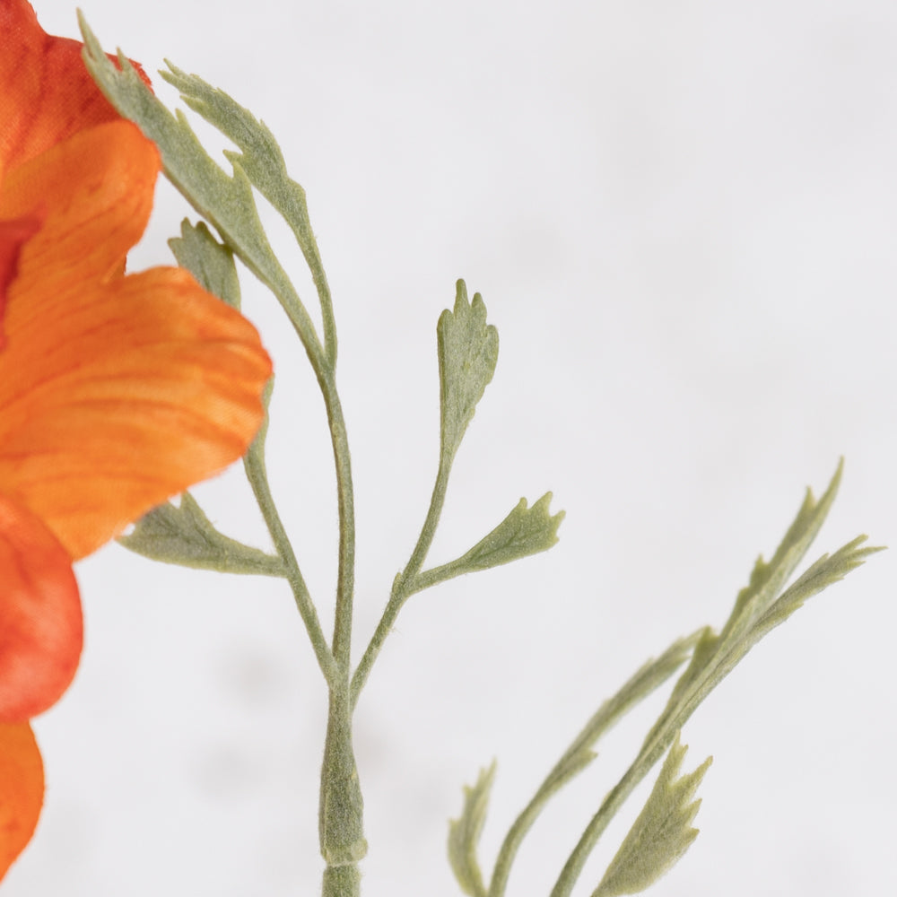A faux anemone flower and stem with leaf detail, in bright orange.
