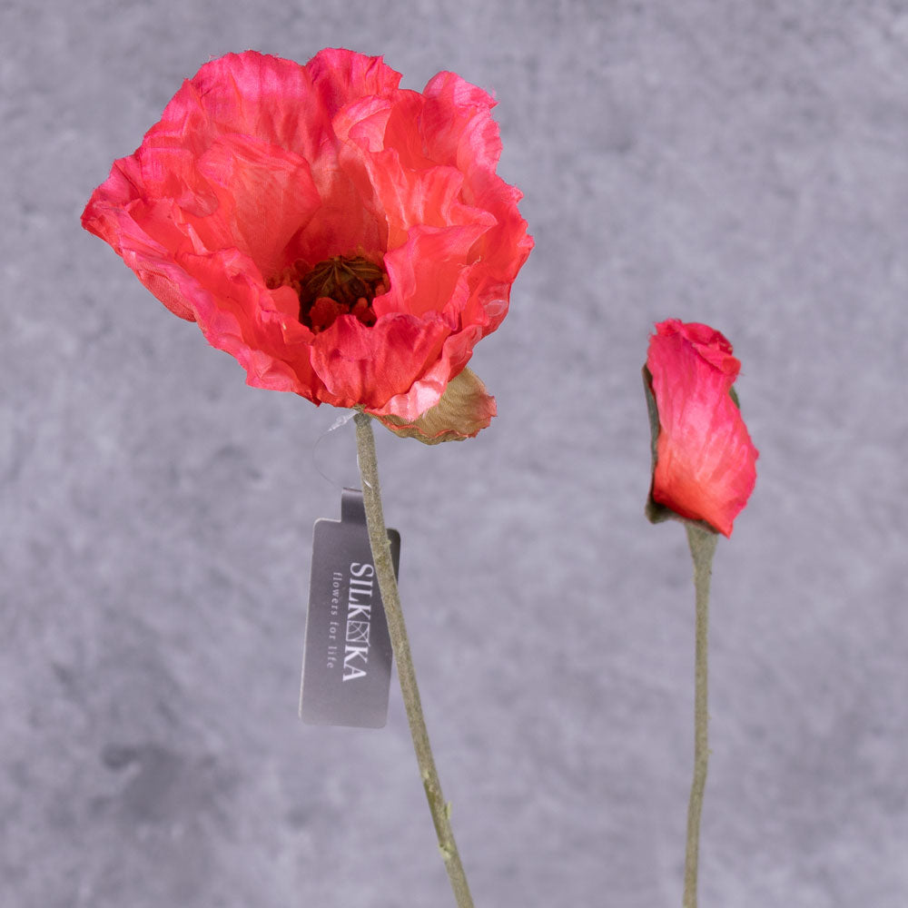 A close up of a faux poppy spray, with flowers in an acid pink colour