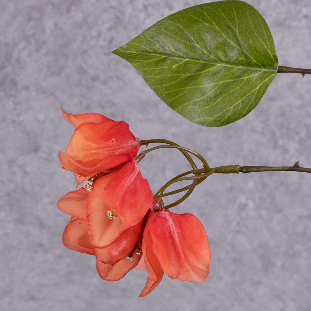A close up shot of a flower cluster from a faux bougainvillea spray, in an acidic orange-red colour