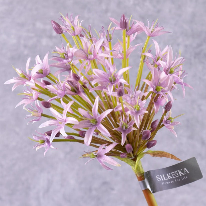 A close up of a single faux allium stem with lilac coloured flower plume