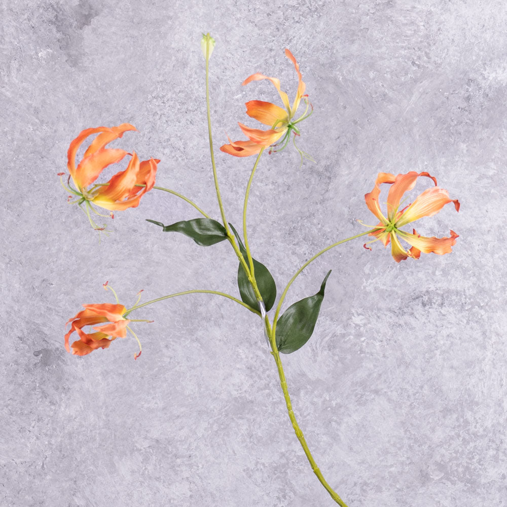 A faux gloriosa spray with 4 orange-yellow flowers, and 1 bud