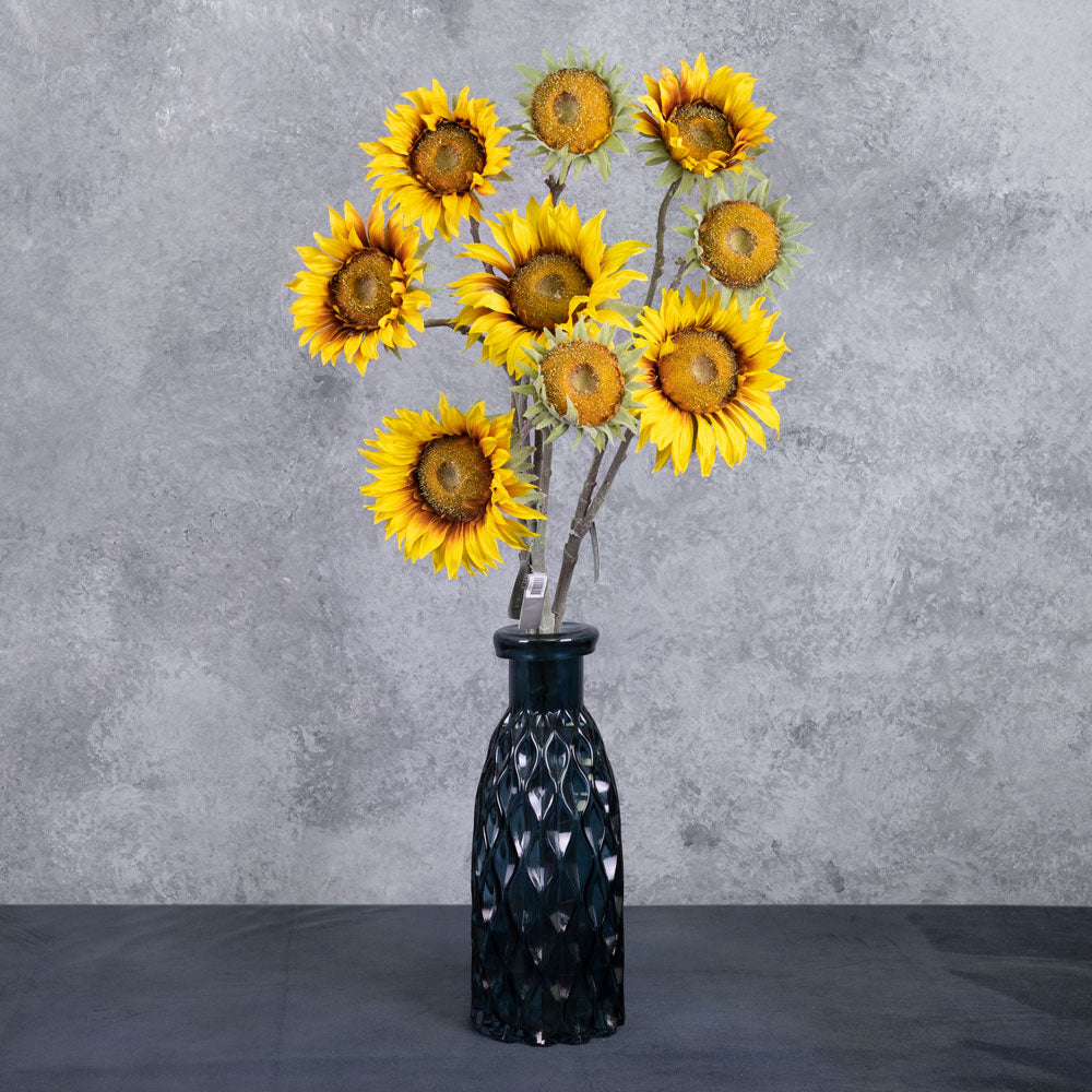 A close up of a single, faux, sunflower head in rich yellow