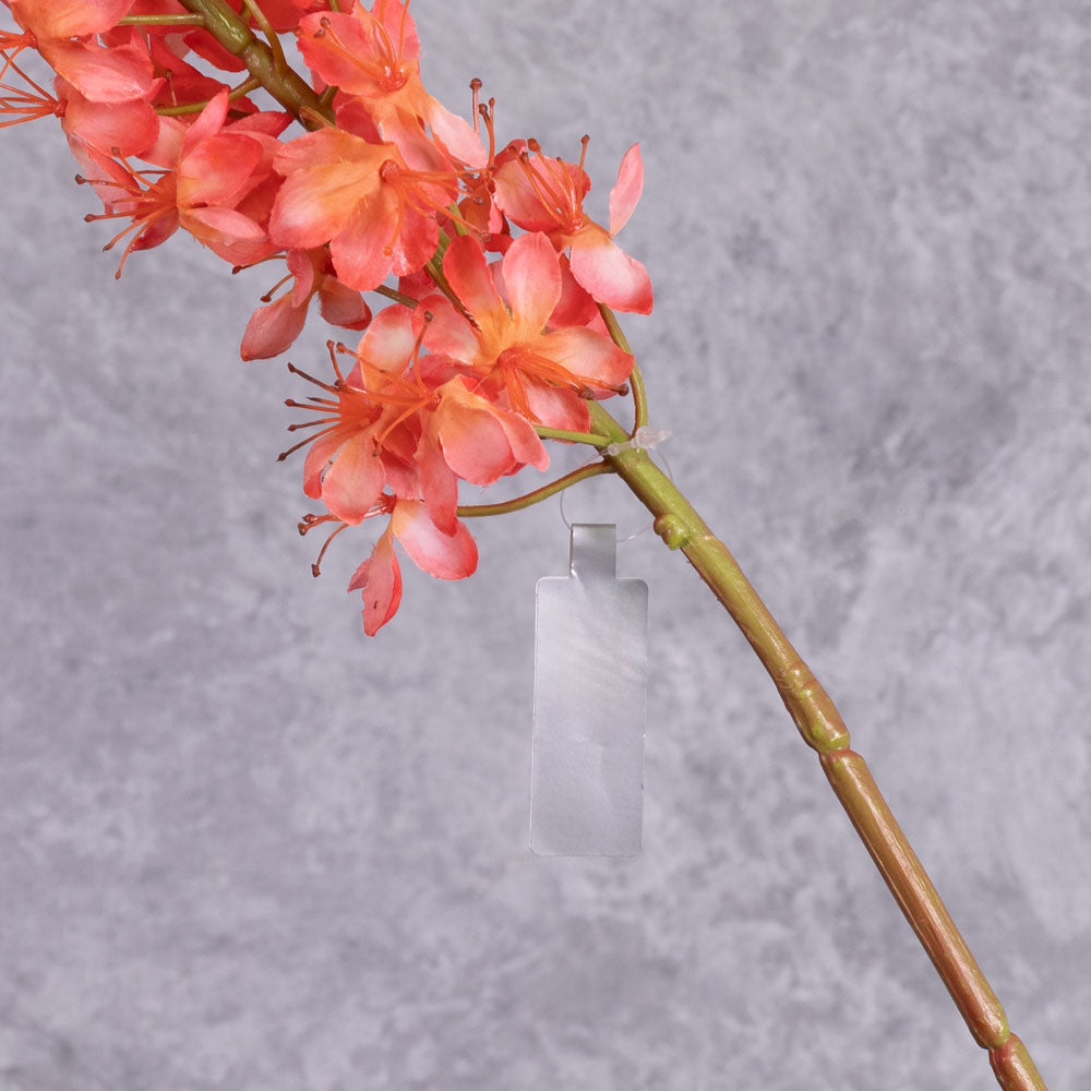 A close up shot of a faux foxtail lily with warm salmon flowers showing detail of the base of the flowers