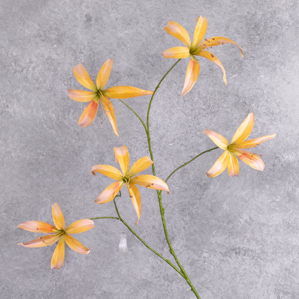 A tall. faux lily spray with peach flowers