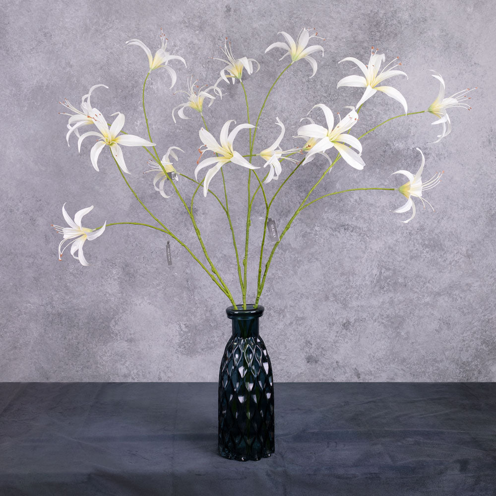 Three tall. faux lily sprays with white-cream flowers, shown in a dark blue glass vase
