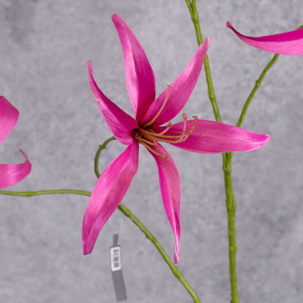 A close up shot of a single, faux lily flower in bright pink