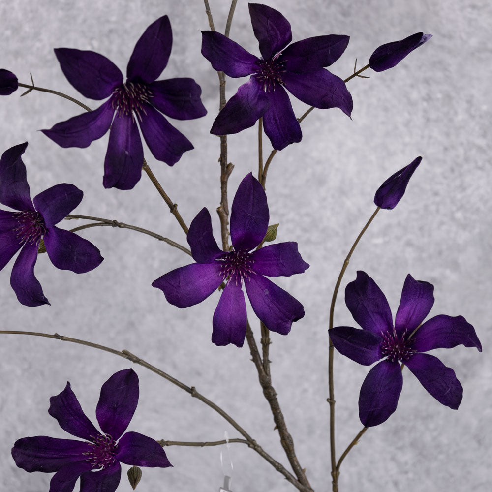 A close up of faux clematis flowers in a deep purple colour
