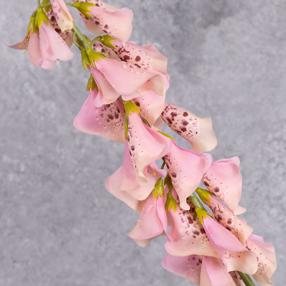 Three faux. pink foxglove stems in a cream coloured oval vase.